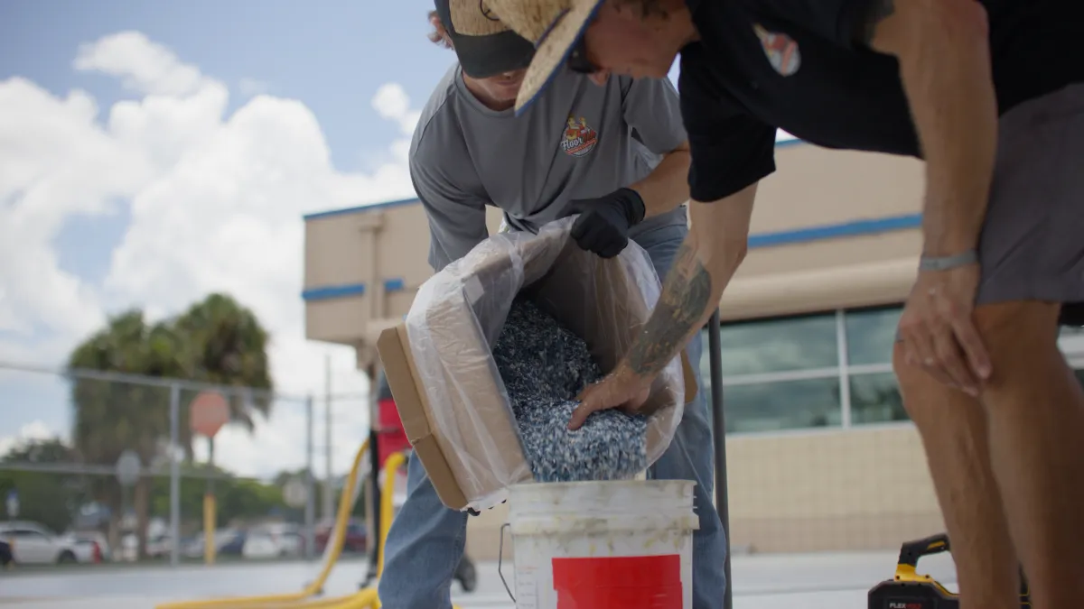 FloorTek team member pouring coating flakes into a mixing bucket